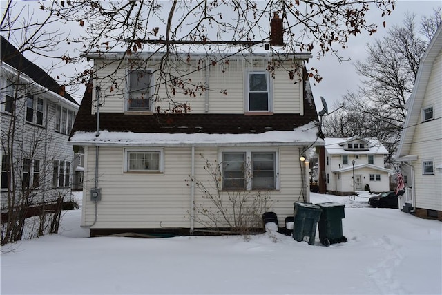 snow covered property featuring a chimney