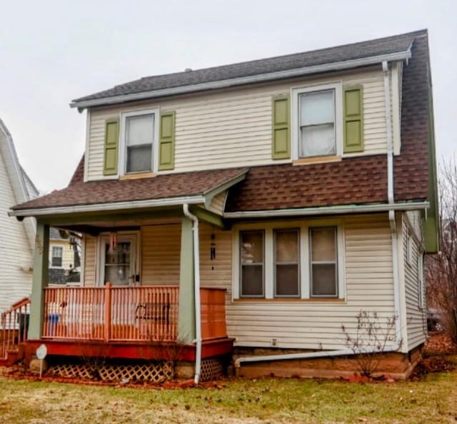 view of front of home featuring covered porch, a front yard, and roof with shingles