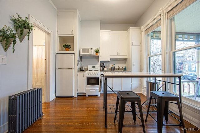 kitchen featuring radiator, white appliances, white cabinets, and open shelves