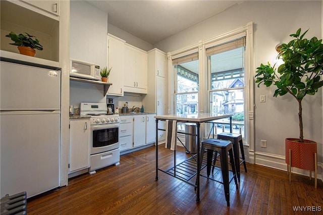 kitchen with white appliances, baseboards, white cabinetry, and dark wood-style flooring