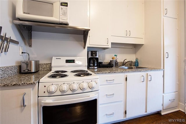 kitchen with stone countertops, white appliances, white cabinets, and a sink