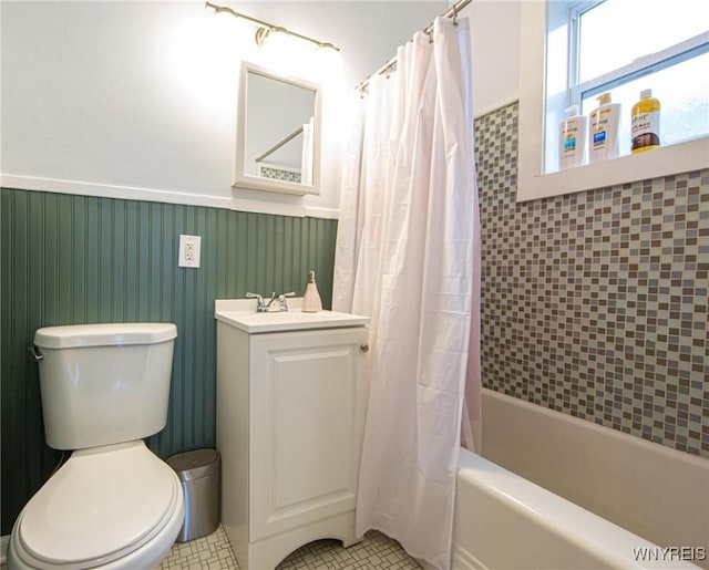 full bath with tile patterned flooring, toilet, a wainscoted wall, vanity, and shower / bath combo with shower curtain