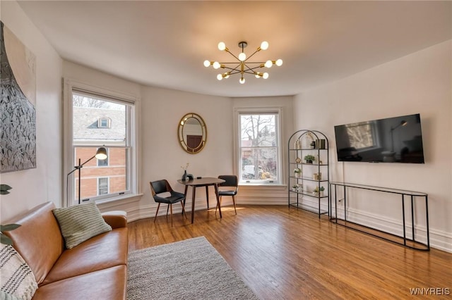 sitting room featuring a healthy amount of sunlight, baseboards, a chandelier, and wood finished floors