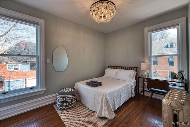 bedroom with dark wood-style floors and multiple windows