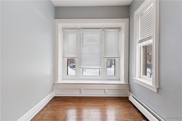 spare room with a baseboard radiator, dark wood finished floors, and baseboards