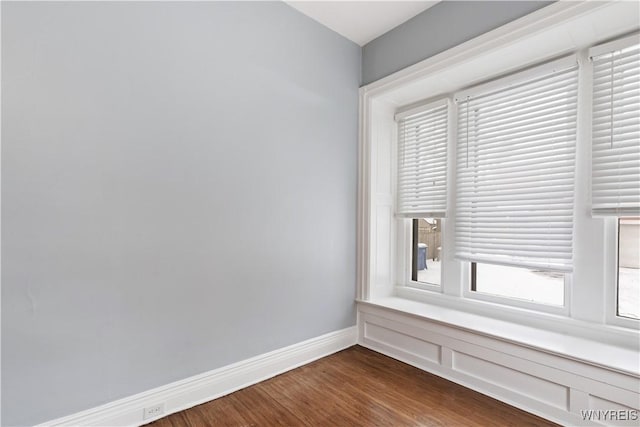 spare room featuring baseboards and wood finished floors