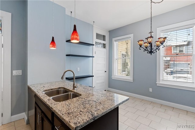 kitchen with light stone counters, a wealth of natural light, a sink, and a center island with sink