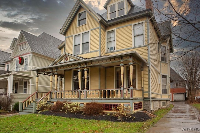 view of front facade featuring covered porch, a detached garage, a chimney, and an outbuilding