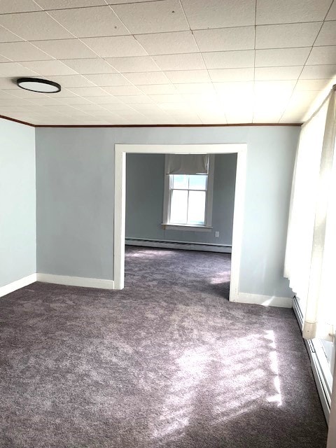 empty room featuring a paneled ceiling, baseboards, and baseboard heating