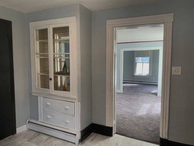 corridor featuring a baseboard heating unit, carpet flooring, baseboards, marble finish floor, and baseboard heating