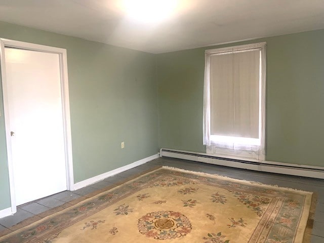 unfurnished room featuring a baseboard radiator and baseboards