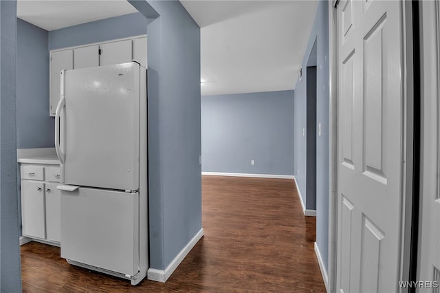 kitchen with white cabinetry, baseboards, light countertops, freestanding refrigerator, and dark wood-style floors