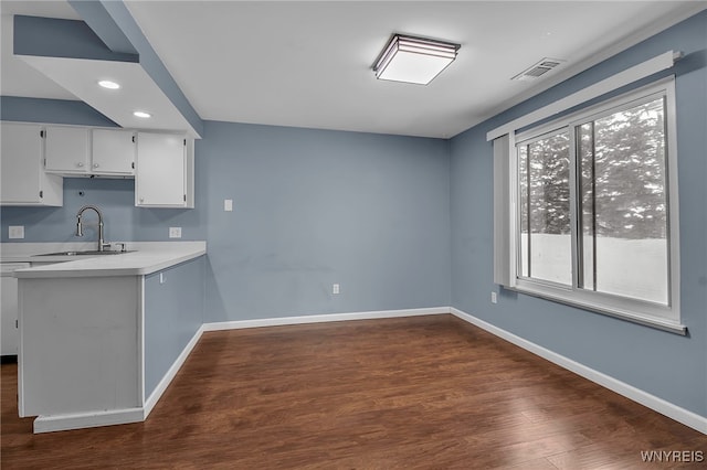 kitchen featuring baseboards, visible vents, light countertops, white cabinetry, and a sink