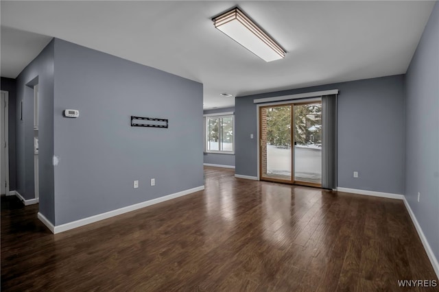 unfurnished room with baseboards and dark wood-type flooring