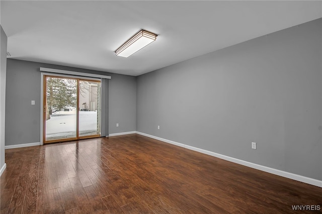 spare room with dark wood-style flooring and baseboards