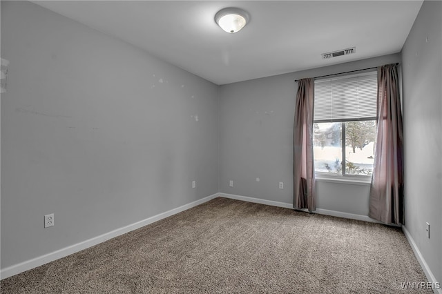 carpeted spare room featuring visible vents and baseboards