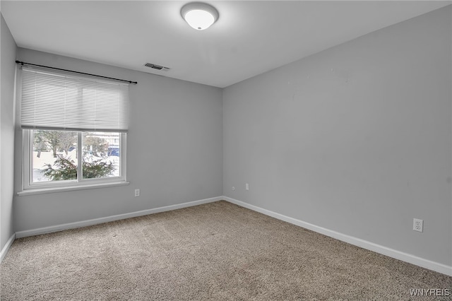 spare room with carpet floors, baseboards, and visible vents