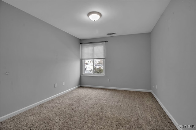 spare room featuring carpet floors, visible vents, and baseboards