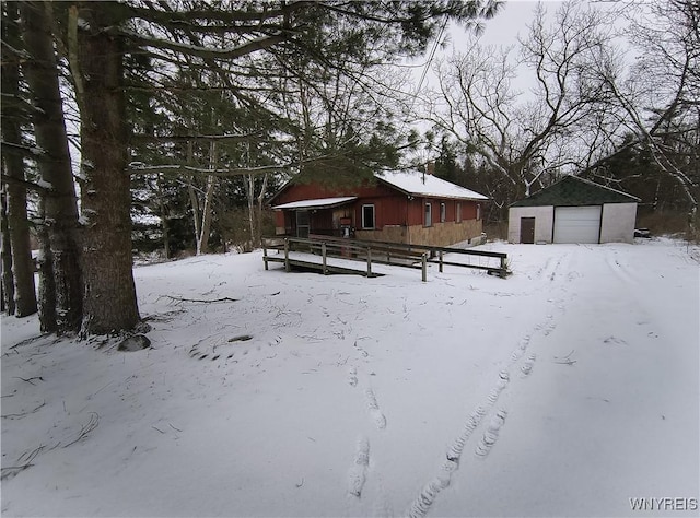 yard layered in snow featuring a garage and an outdoor structure