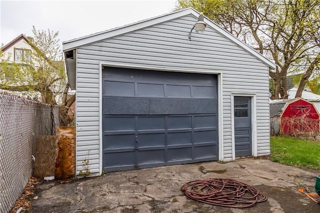 detached garage featuring fence and driveway