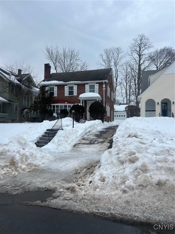 view of front of home with a chimney and brick siding