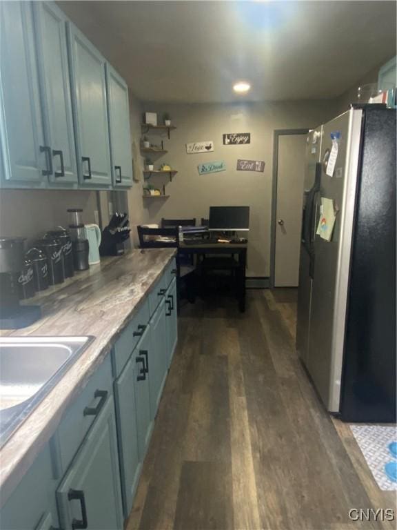 kitchen featuring a sink, light countertops, dark wood-style flooring, and freestanding refrigerator