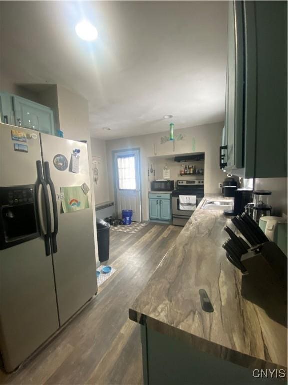 kitchen featuring green cabinets, appliances with stainless steel finishes, dark wood-style flooring, and a sink