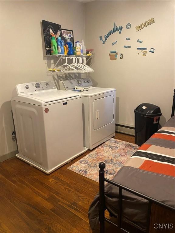 laundry area featuring a baseboard radiator, laundry area, washing machine and dryer, and dark wood-type flooring