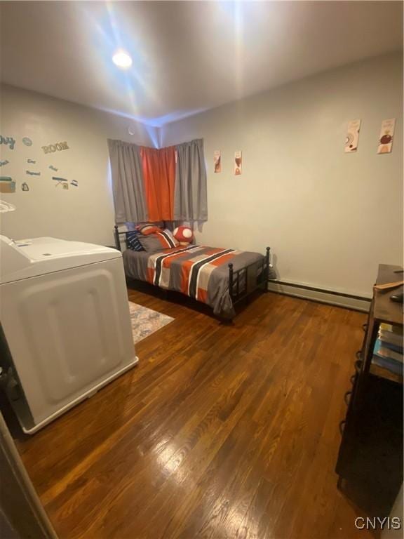 bedroom featuring a baseboard heating unit, dark wood-type flooring, and washer / dryer