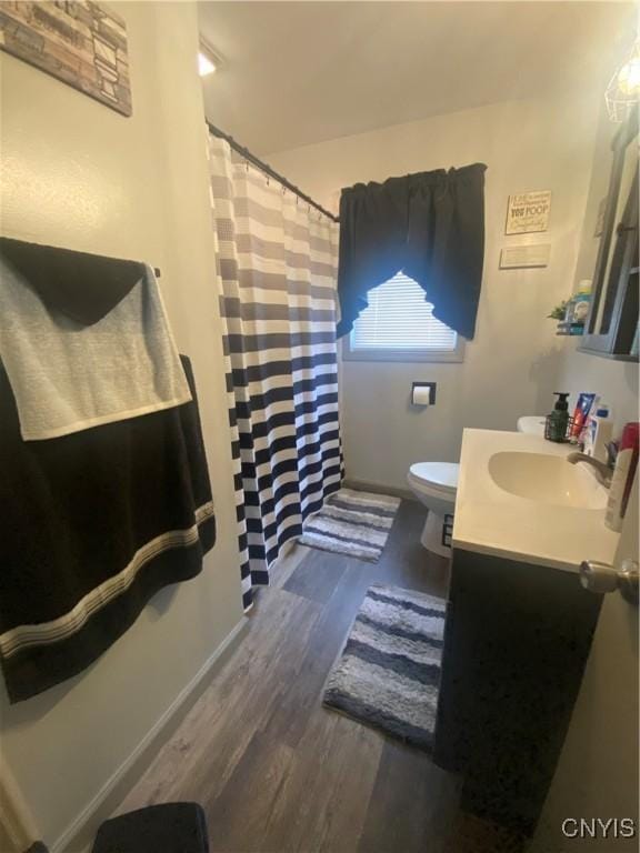 bathroom featuring baseboards, vanity, toilet, and wood finished floors