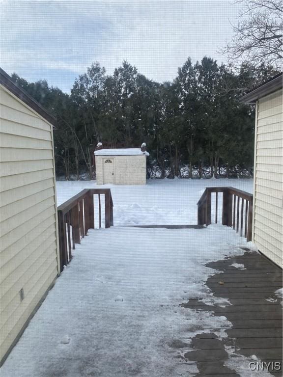 snow covered deck with an outbuilding and a shed