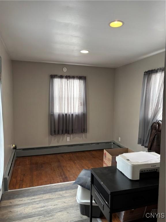 home office featuring baseboard heating, wood finished floors, and recessed lighting