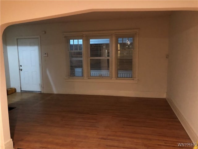 interior space featuring baseboards and dark wood-type flooring