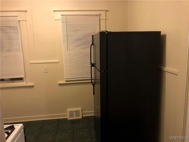 kitchen featuring baseboards, visible vents, and freestanding refrigerator