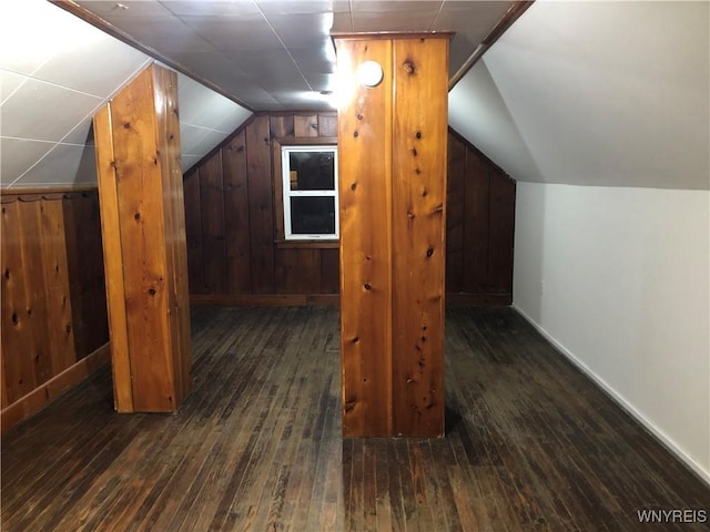 additional living space featuring lofted ceiling, wood walls, dark wood-style flooring, and baseboards