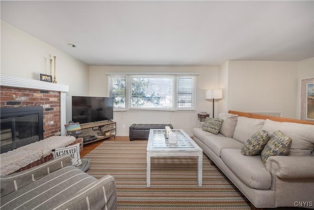 living area featuring a fireplace, baseboards, and wood finished floors