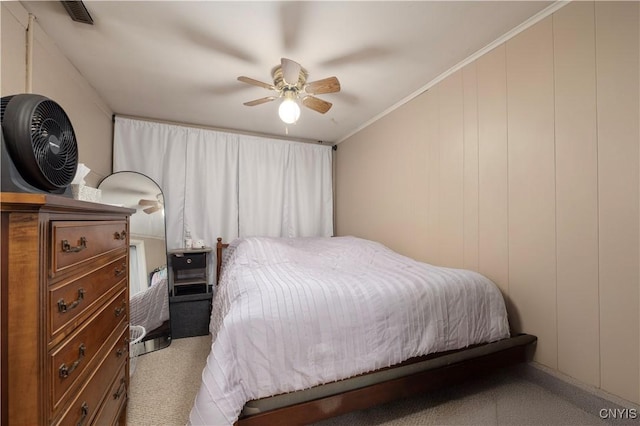 bedroom featuring visible vents, a decorative wall, a ceiling fan, and ornamental molding