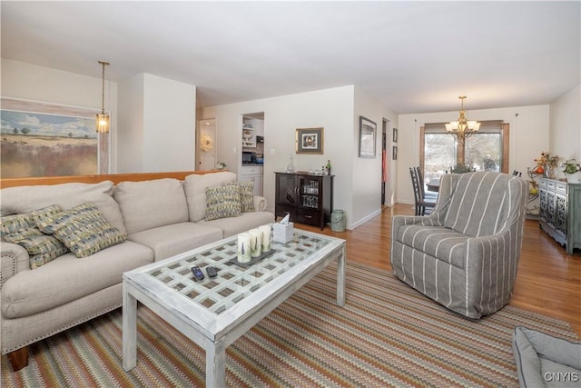 living room featuring a notable chandelier, baseboards, and wood finished floors