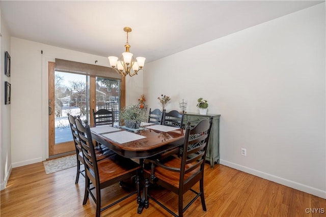 dining area with light wood-type flooring, baseboards, and a chandelier