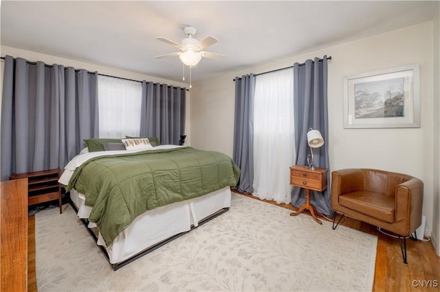 bedroom with a ceiling fan, multiple windows, and wood finished floors