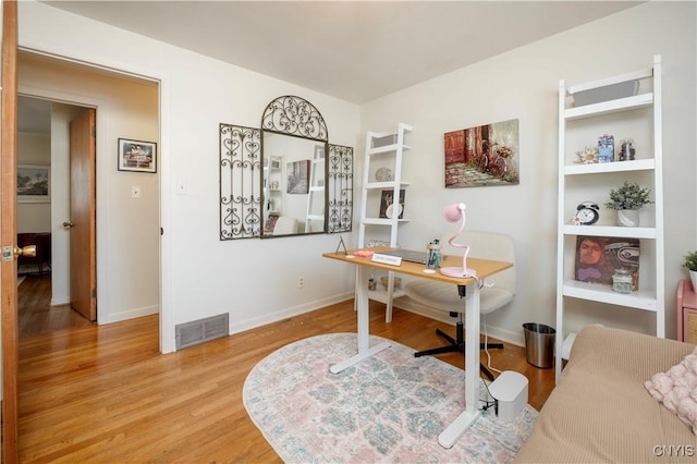 office area with visible vents, baseboards, and wood finished floors