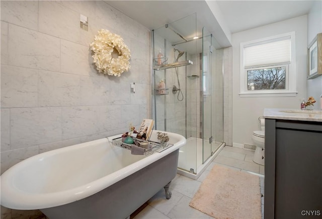 full bathroom with tile walls, a freestanding bath, toilet, a shower stall, and vanity