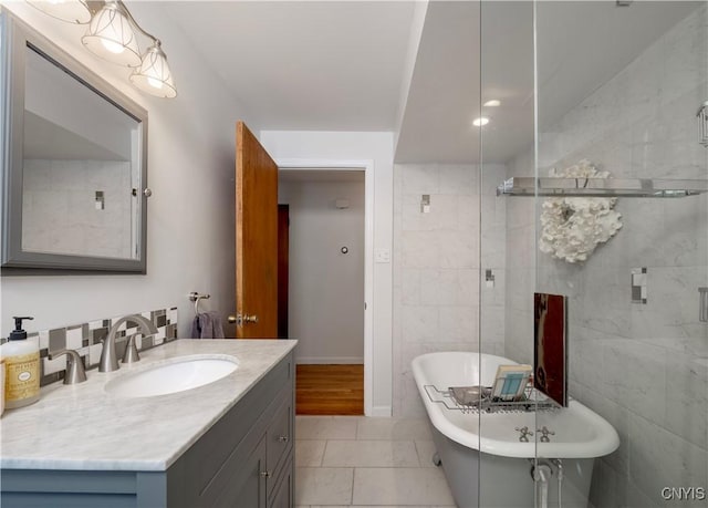 bathroom featuring a freestanding tub, baseboards, tile walls, and vanity