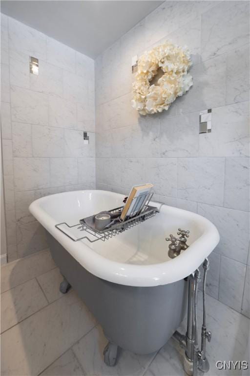 bathroom featuring a freestanding tub, marble finish floor, and tile walls