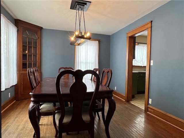 dining area with a healthy amount of sunlight, an inviting chandelier, baseboards, and dark wood-style flooring