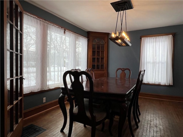 dining space featuring a notable chandelier, baseboards, visible vents, and dark wood-type flooring