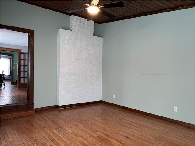 empty room featuring ceiling fan, brick wall, wooden ceiling, and wood finished floors