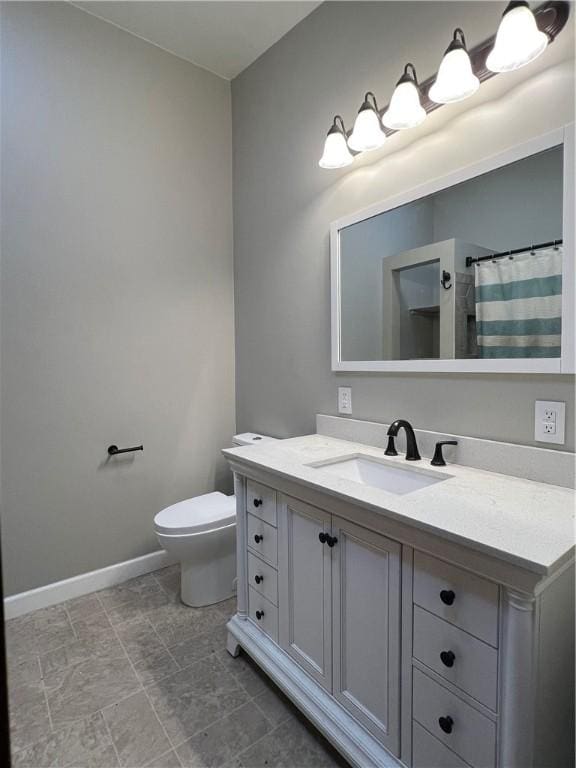 bathroom with toilet, a shower with shower curtain, vanity, and baseboards