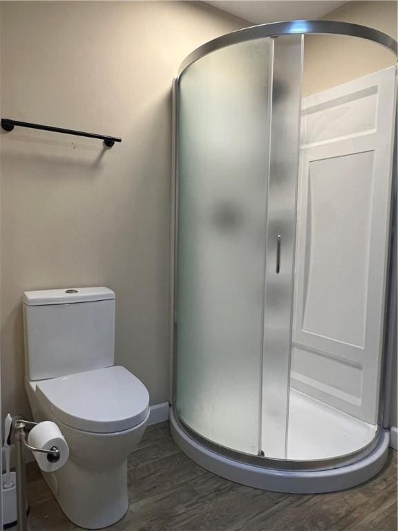 full bath featuring a stall shower, wood finished floors, toilet, and baseboards