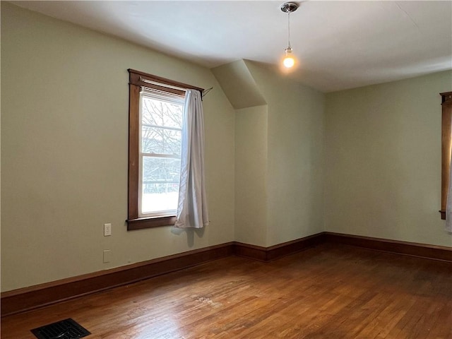 bonus room with wood finished floors, visible vents, and baseboards